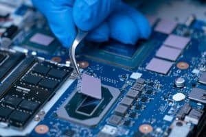 Technician repairing inside of thermal pad for Integrated Circuit. the concept of data, hardware repairing, upgrade technology. Thermal pad applied to a PCB